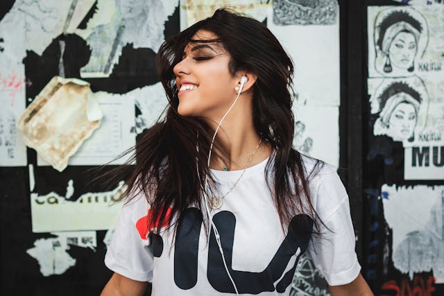 How to Turn Off Pandora 2 Smiling woman listening to music with wired earbuds in front of street art