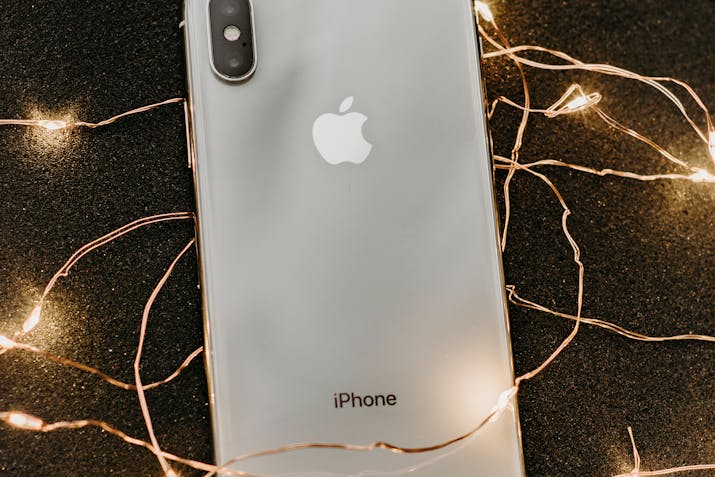 Facts About Orange Dot On Iphone 1 Silver Apple iPhone with string lights on black background