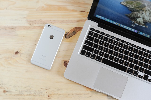Unlock the Power of iPhone USB Tethering 3 Apple iPhone placed beside open MacBook on wooden desk