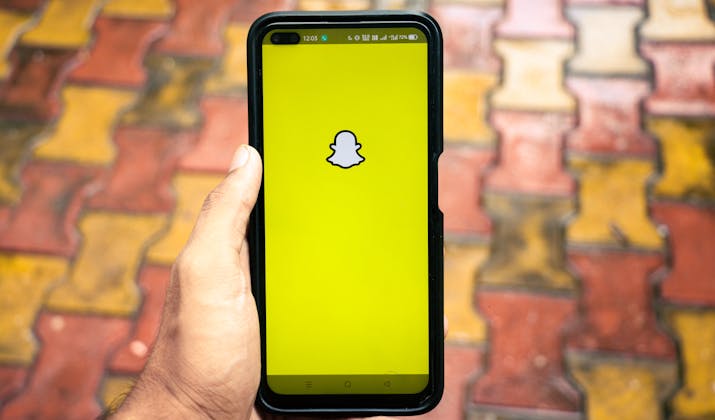 What Happens If You Block Someone On Snapchat? 3 User holding smartphone with Snapchat logo on yellow screen