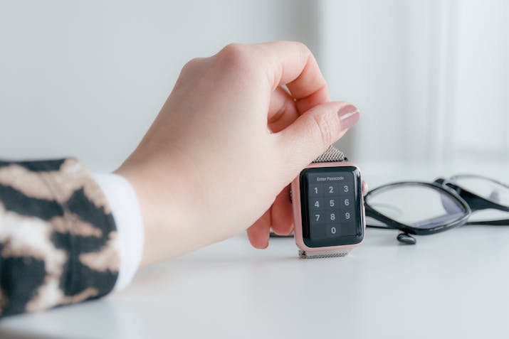 Apple Watch Wrist Detection 2 Hand entering passcode on Apple Watch next to eyeglasses on desk.