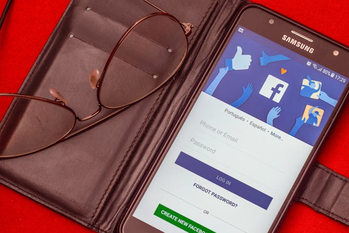 What Do The Green Dots Mean On Facebook ? 1 Samsung phone in a wallet case showing the Facebook login screen with glasses on a red background.