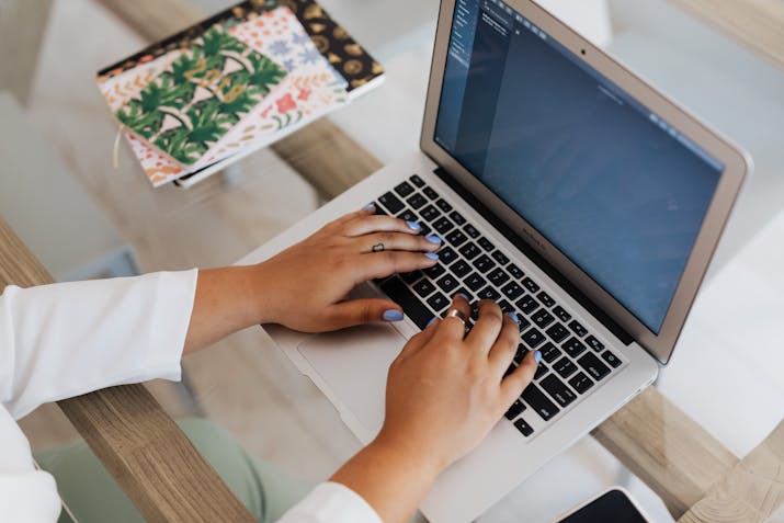 How To Unlock Your Macbook Air Bypassing Passwords 1 Hands typing on a MacBook Air at a glass desk with notebooks