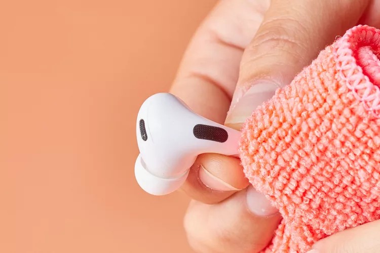 Hand cleaning an AirPods Pro earbud with a microfiber cloth