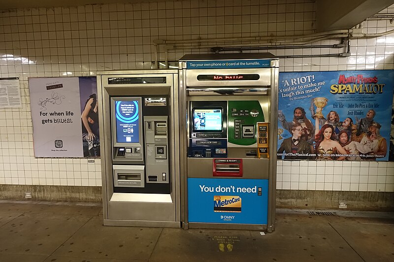 NYC subway fare machines: an OMNY kiosk beside a MetroCard vending machine in a tiled station