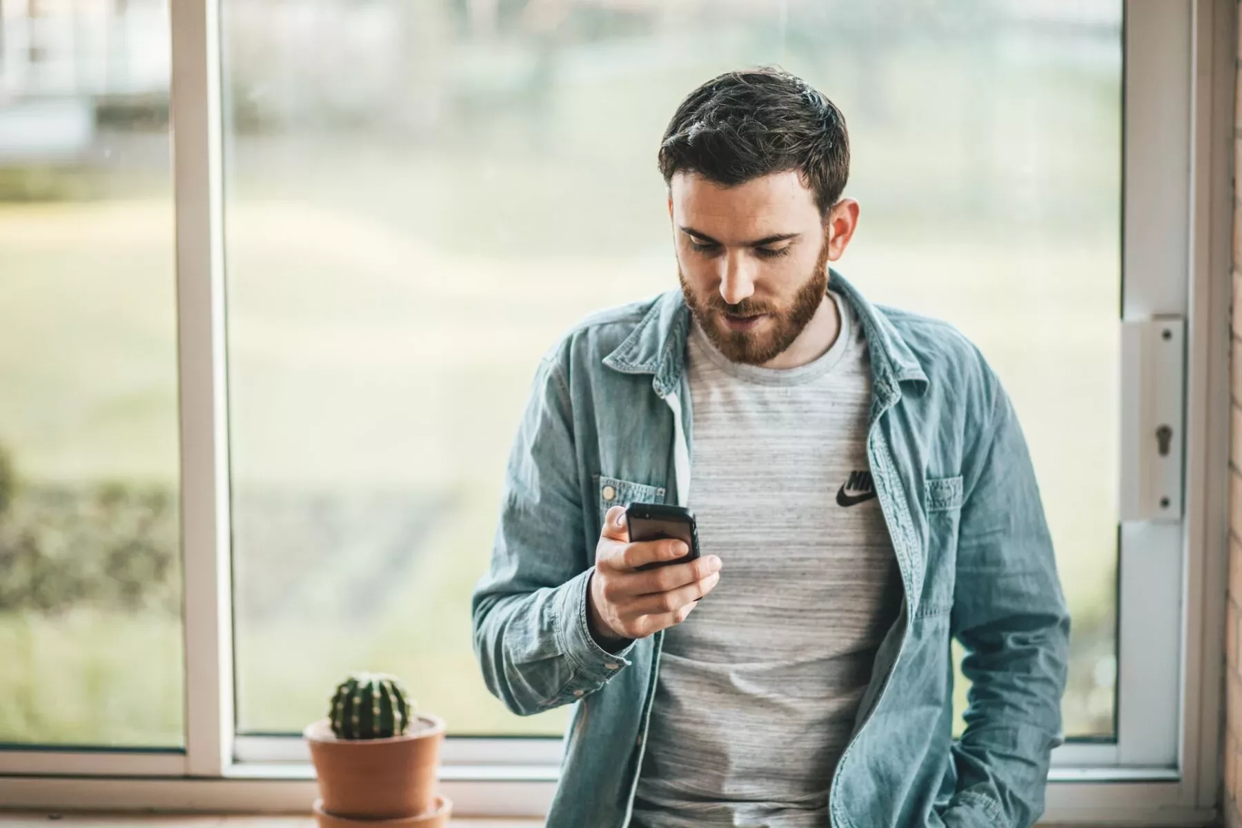 Amazon Photos Facts & FAQ 1 Man looking at smartphone by a window