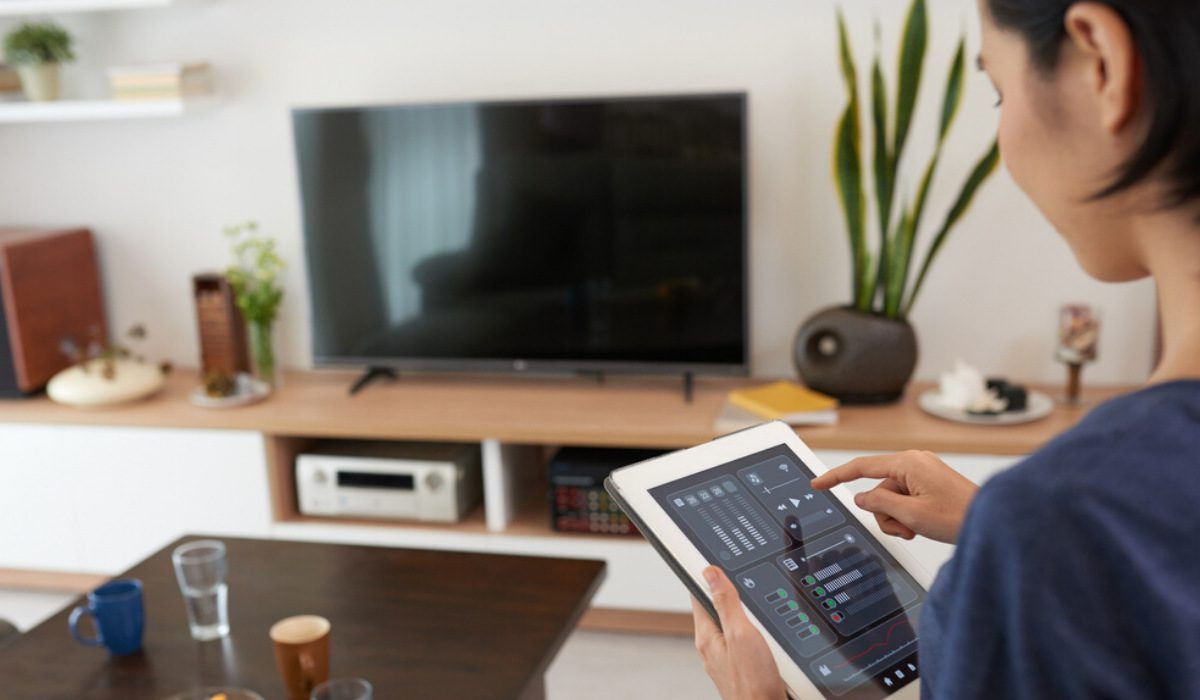 A woman using a touch pad device to control her home.