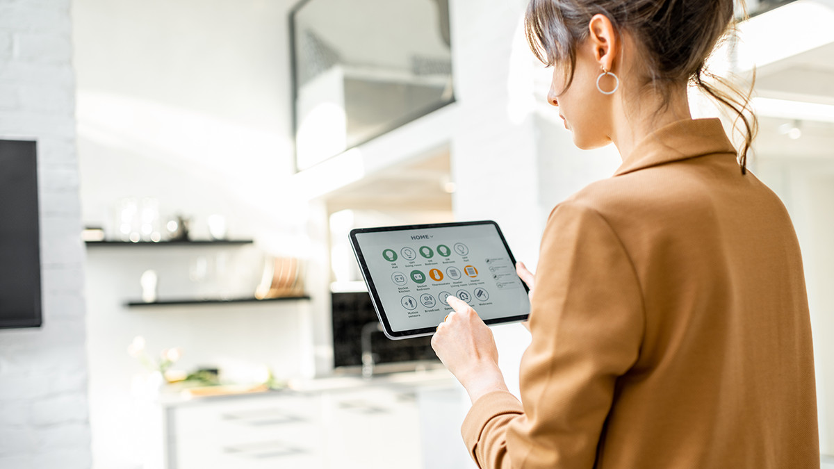 A woman using a touch pad device to control her home.