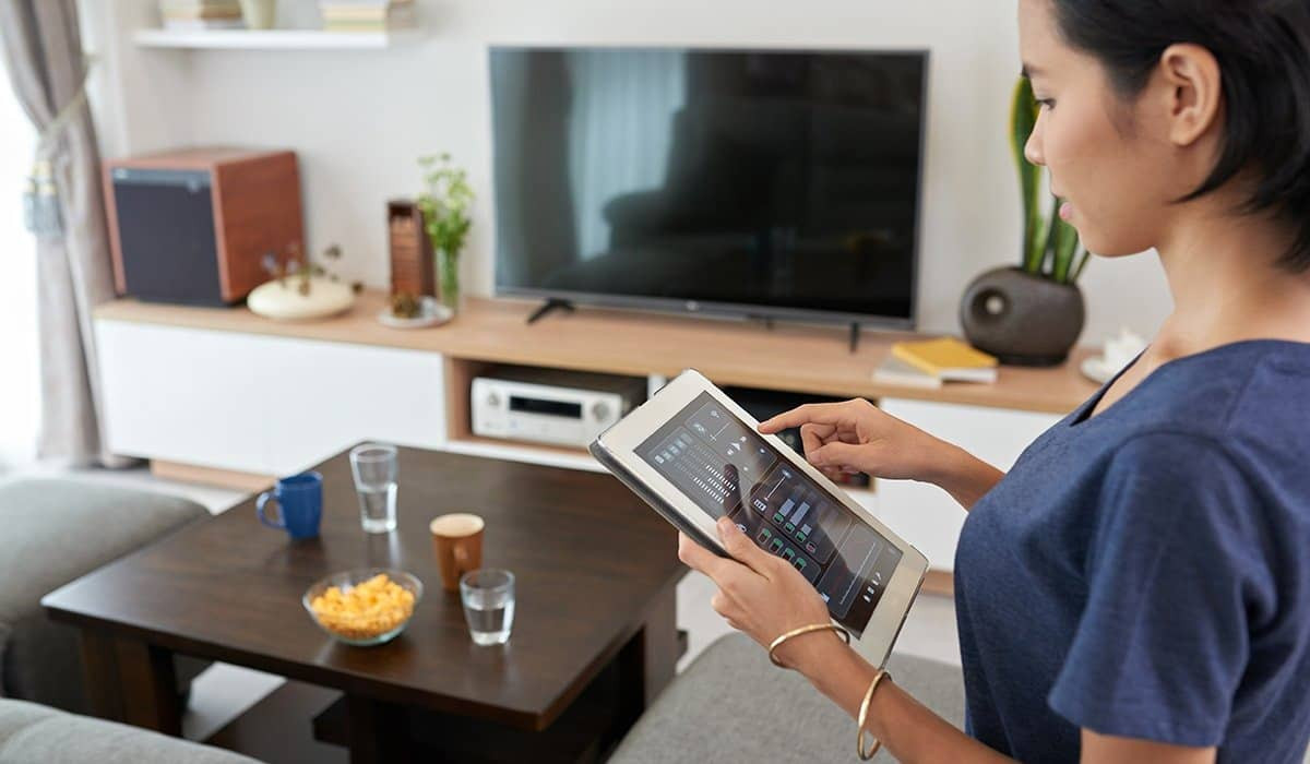 A woman using a touch pad device to control her home.